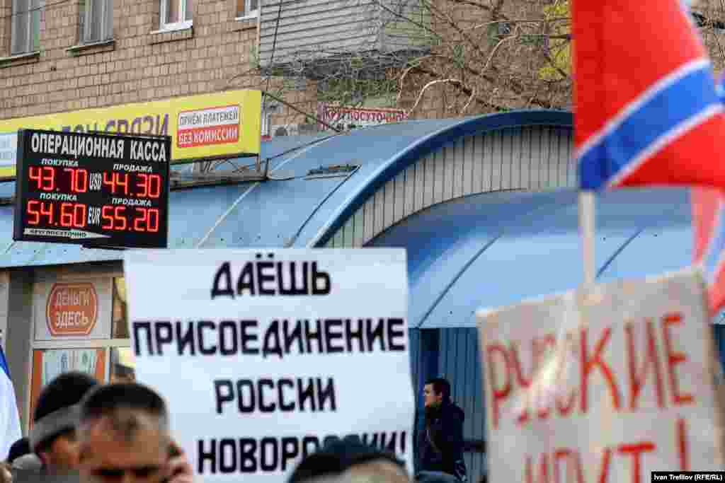 Лозунг "Даешь присоединение России к Новопроссии" хорошо смотрится на фоне табло с текущими курсами валют