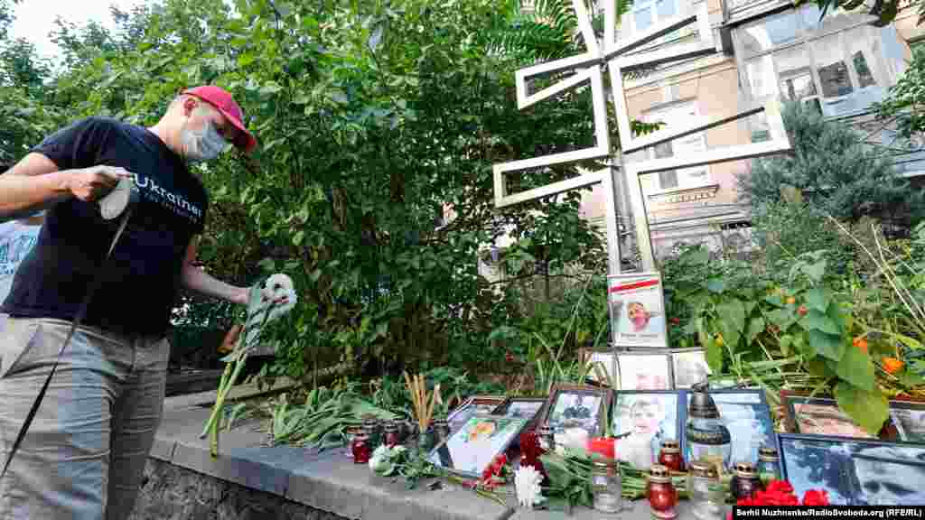 Чоловік покладає квіти до пам'ятного хреста жертвам режиму Лукашенка