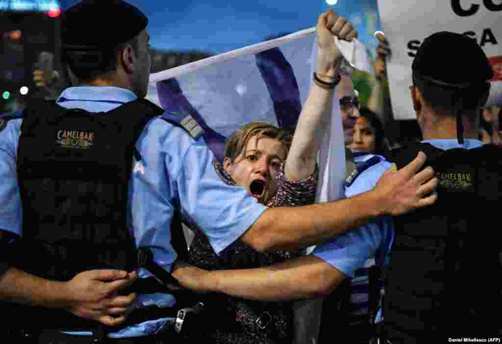 Протестуючі вигукують антиурядові гасла під час акції протесту перед будівлею уряду в Бухаресті, Румунія, 30 травня. Близько 2000 людей вийшли на мітинг після того, як  більшість суддів Конституційного суду Румунії ухвалили рішення, яке зобов'язує президента країни звільнити головного антикорупційного прокурора країни Лауру Ковеші. Тоді румуни вийшли на масові протести з вимогою захистити її. Уряд звинуватив Ковеші в порушенні Конституції, але її прихильники заявили, що вона розслідувала корупцію серед політичної еліти Румунії. (AFP/Daniel Mihailescu)