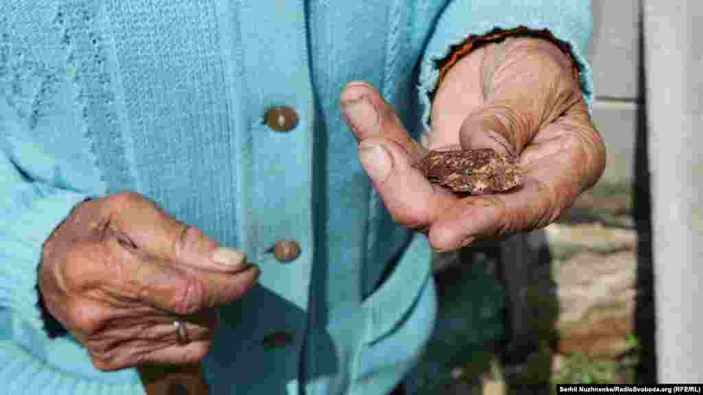 Марія показує нам металеві осколки, які розкидані не лише по її подвір’ю, а й по усьому селу