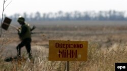 Український військовий позначає небезпечні місця знаком «Обережно міни» біля Маріуполя, вересень 2014 року