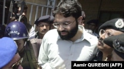 In this file photo taken on March 29, 2002, Pakistani police surround a handcuffed Ahmed Omar Sheikh as he exits a court in Karachi.