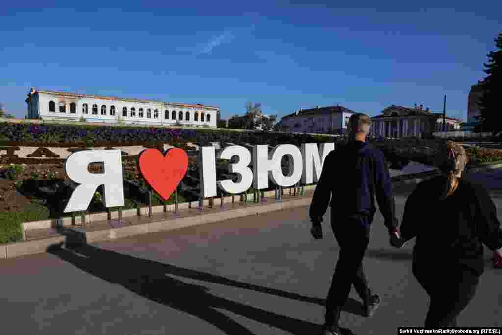 Український військовий у звільненому Ізюмі, вересень 2022 року / Праворуч: початок жовтня 2024-го В Ізюмі працюють комунальні служби, державні установи, гуманітарні організації, ринки, магазини, військторг і спортзал. Але більшість підприємств, що були розбиті обстрілами й розкрадені  мародерами, так і не відновили роботу. Багато його колишніх працівників теж виїхали з міста «Виживаємо коштом бюджетників, і військових»,  говорять місцеві жителі  