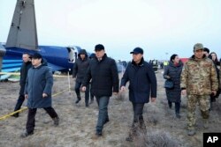 Члени слідчої групи та місцеві чиновники проходять повз уламки Embraer 190 авіакомпанії «Азербайджанські авіалінії», що лежить на землі біля аеропорту Актау (Казахстан), 26 грудня 2024 року