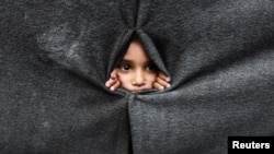 Raseljeno palestinsko dijete gleda kroz zaklon napravljen od ćebadi u školi koju vodi UNRWA nakon što je američki predsjednik Donald Trump objavio da su se Izrael i Hamas složili oko prve faze primirja u Gazi, Han Junis na jugu Pojasa Gaze, 9. oktobar 2025.