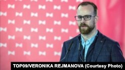 Ондржей Коларж, який повідомив, що зараз переховується, заявив телеканалу Prima TV, що йому не можна розголошувати деталі справи щодо нього, а також мера Праги Зденєка Гржиба і ще одного голови району Павела Новотного