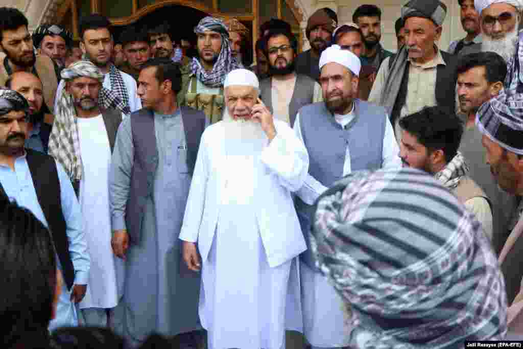 Ismail Khan (on telephone), a veteran of the Soviet-Afghan war of the 1980s, with supporters as he prepares to defend the area against the Taliban advance on July 9. Khan survived an assassination attempt by the Taliban in 2009. 