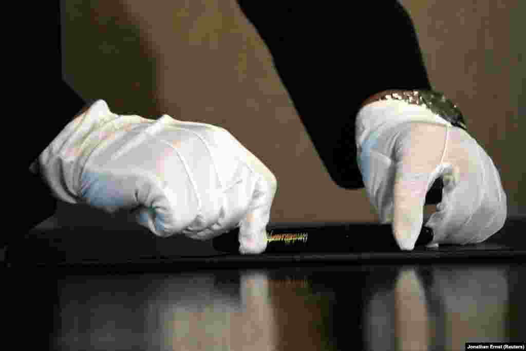 Північнокорейський помічник кладе на стіл ручку – її ретельно протерли для лідера Північної Кореї перед церемонією підписання документа з президентом США