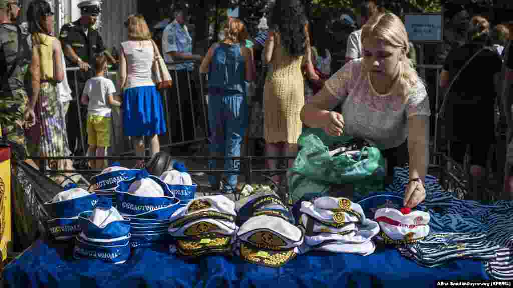 Девушка раскладывает сувенирные головные уборы для «фанатов» Черноморского флота