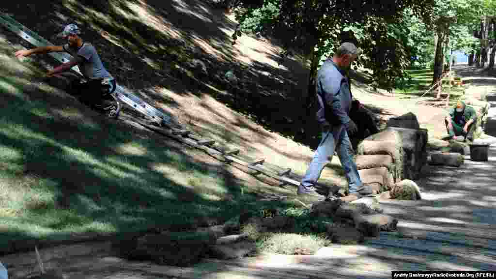 Працівники комунальних служб замінюють газон на Володимирській гірці.