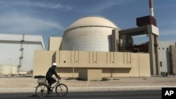 A worker rides a bicycle past the reactor building of the Bushehr nuclear power plant in Iran. (file photo)
