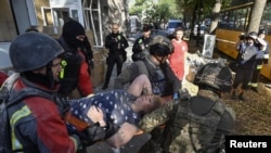 Рятувальники та співробітники поліції несуть на ношах мешканку, яка постраждала від російського авіаудару. Запоріжжя, 29 вересня 2024 року