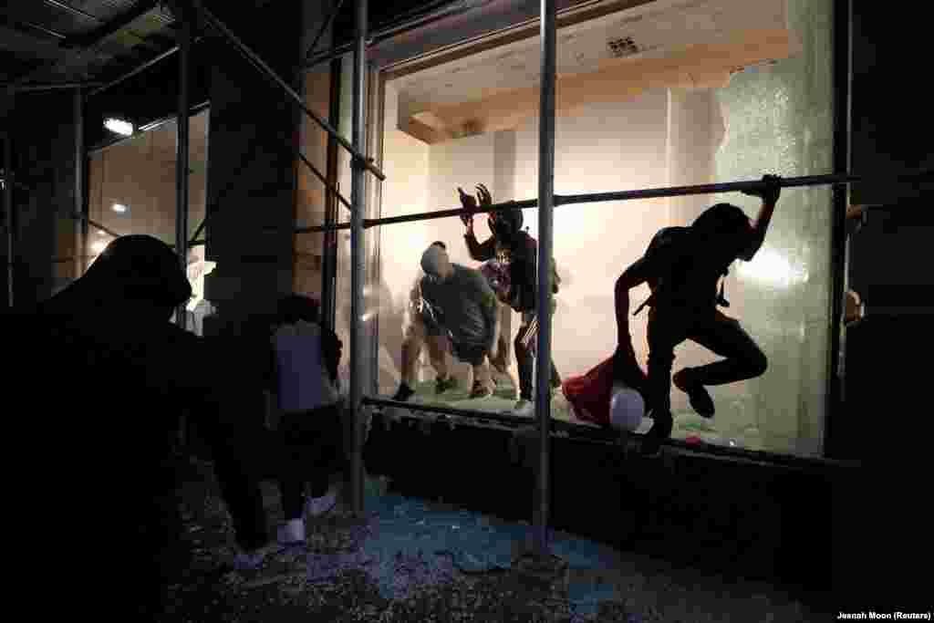 Чоловік вистрибує з магазину через розбиту вітрину в Нью-Йорку. У місті тривають акції протесту через смерть Джорджа Флойда. Нью-Йорк, 2 травня 2020 року (Фото REUTERS/Jeenah Moon)