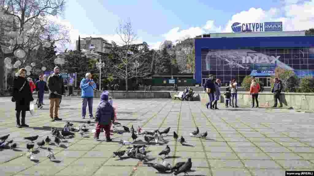 Теплая солнечная погода в выходной день позвала родителей с детьми на главную площадь города. В том числе, чтобы покормить голубей