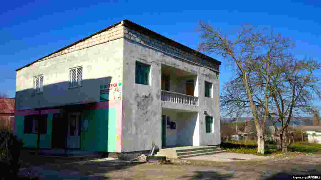 Здание в центре села, где на первом этаже размещены аптека и отделение почты, а на втором – библиотека.