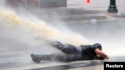 Струя водомета сбивает с ног демонстранта в Анкаре. 16 июня 2013 г.