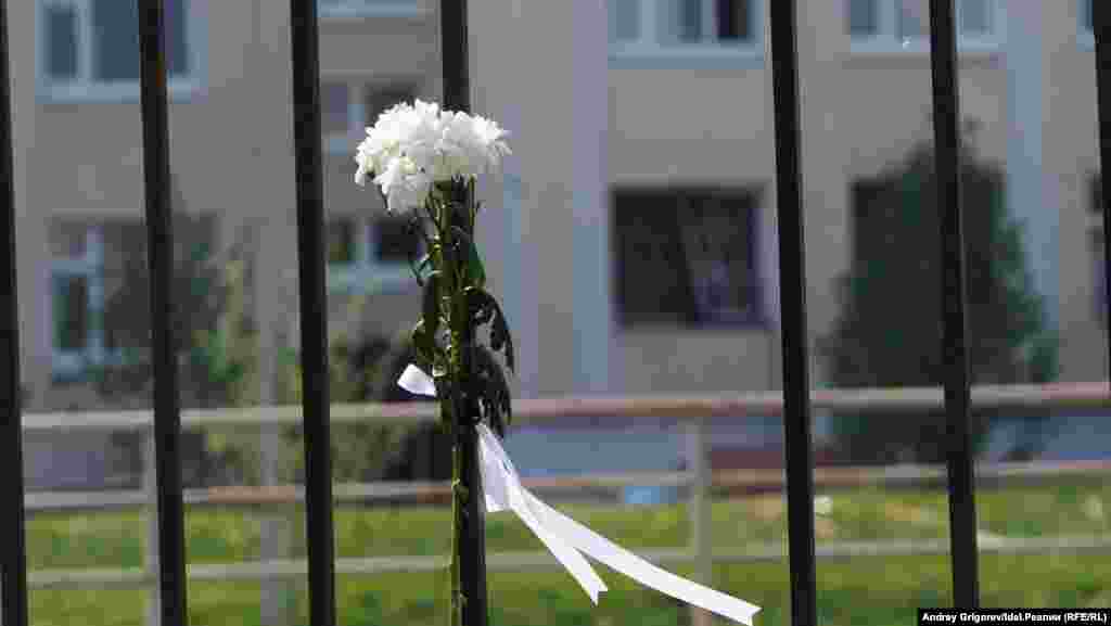 Букетик цветов напротив выбитого взрывом окна. 