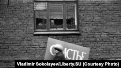 Фото Владимира Соколаева. Женщина с плакатом спешит на первомайскую демонстрацию. Новокузнецк. 1983