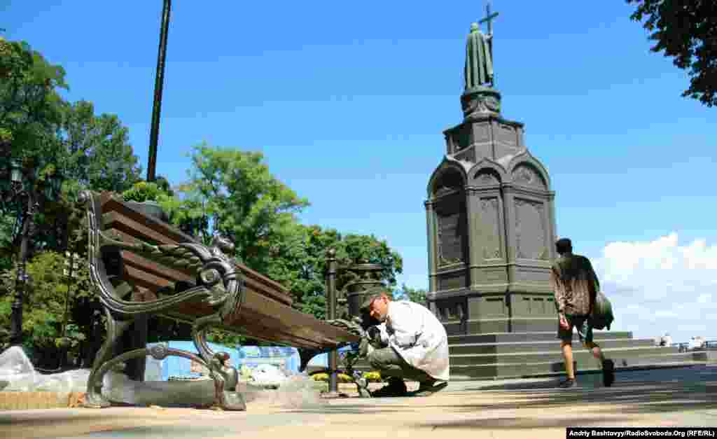 Працівник комунальних служб фарбує баки для сміття на Володимирській гірці.