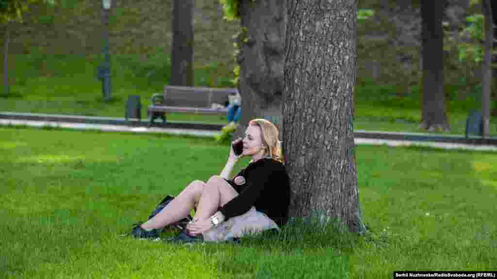 Девушка говорит по телефону на газоне в парке «Владимирская горка»