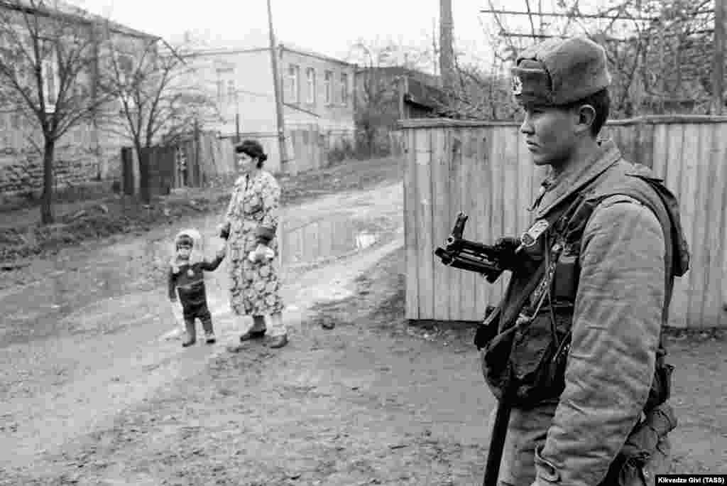 Радянський солдат стоїть на сторожі в Цхінвалі в грудні 1990 року.  Москва направила до Південної Осетії контингент військ МВС СРСР, щоб «запобігти сутичкам та кровопролиттю», але Тбілісі висловив протест проти цього «втручання» Кремля і відправив туди своїх бійців