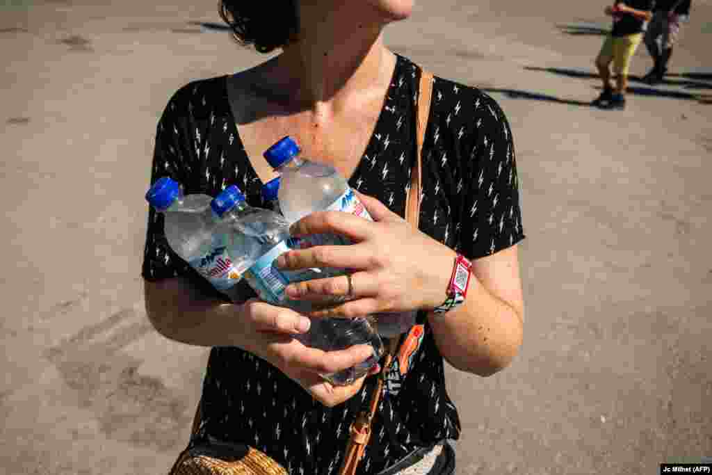 Učesnica muzičkog festivala na jugu Francuske nosi boce hladne vode, 29. juna.