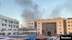 Smoke rises as displaced Palestinians take shelter at Al Shifa hospital, amid the ongoing conflict between Hamas and Israel, in Gaza City