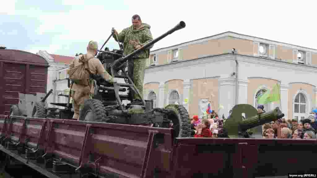 На платформе поезда – орудия и одетые в советскую военную форму актеры. Они фотографируются с местными жителями, поднимают на руки детей и размещают их поближе к орудиям