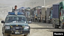 A police vehicle drives past trucks carrying voting materials in the Afghan capital, Kabul, on September 16.