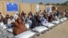 Afghans sit beside sacks of food grains distributed as aid by the World Food Programme in Kandahar on October 19.