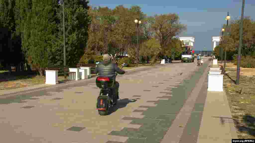 Электроскутер мчится по главной аллее парка