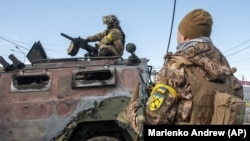 Українські військовослужбовці оглядають знищений російський піхотний броньований автомобіль «Тигр» після бою в Харкові, 27 лютого 2022 року