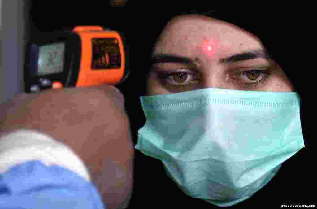 Працівник залізниці перевіряє температуру пасажирів у Карачі 20 травня 2020 року після відновлення залізничного сполучення в Пакистані на тлі пом’якшень обмежувальних заходів, запроваджених через коронавірус. Уряд країни прагне відновити економіку і допомогти людям у їхньому щоденному житті після спаду коронавірусної пандемії