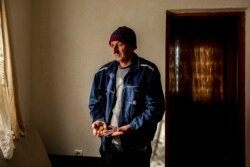 Huso Halilović drži u rukama sat i češalj koji su jedina uspomena na njegovog oca koji je ubijen tokom genocida u Srebrenici.