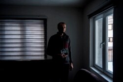 Ahmed Hrustanović drži u rukama fotografije članova bliže familije koji su ubijeni tokom genocida u Srebrenici.