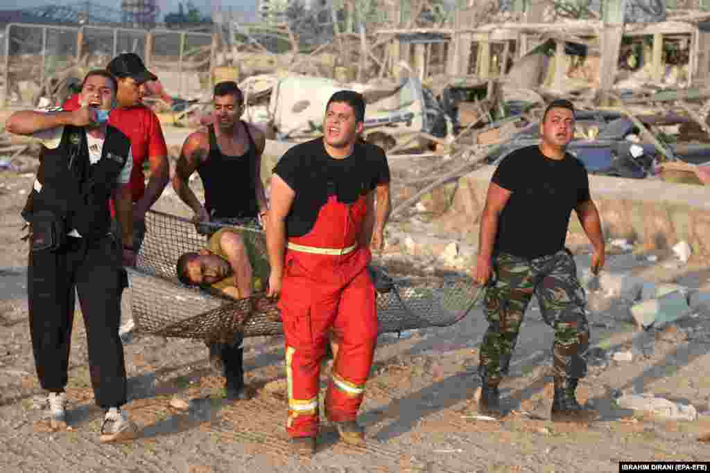 На фото від 4 серпня: пораненого чоловіка евакуюють з місця вибуху.  За словами директора ліванського Червоного Хреста Джорджа Кеттанеха, Червоний Хрест координує дії з Міністерством охорони здоров’я, щоб морги приймали жертв, оскільки лікарні переповнені. Ліванське Міністерство охорони здоров’я раніше заявляло про 73 загиблих і понад чотири тисячі поранених внаслідок вибуху, що стався в районі порту. Сьогодні у Червоному Хресті повідомили, що кількість загиблих зросла до 100