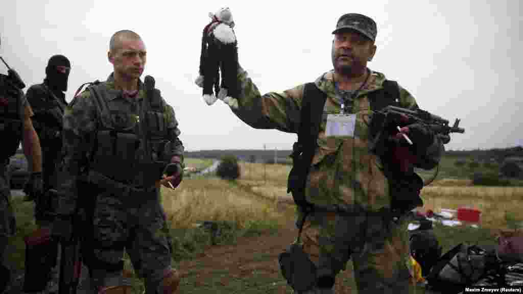 Бойовик російських гібридних сил тримає іграшку, виявлену на місці падіння уламків «Боїнга» Малайзійських авіаліній рейсу МН17, збитого російською установкою «Бук», в результаті чого загинуло 298 людей, в тому числі 80 дітей. Донеччина, неподалік села Грабове, 19 липня 2014 року. Літак був збитий 17 липня. Спільна міжнародна слідча група (JIT) вважає, що цією установкою, з високою ймовірністю, управляли російські військові, і вона була привезена з Росії в Україну незадовго до катастрофи. За даними JIT, «Бук» із бортовим номером 332 був на озброєнні 53-ї бригади ЗС Російської Федерації (військова частина 32406)