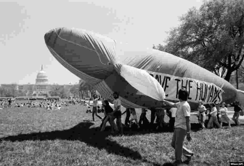 Молодь із Вашингтона відзначає День Землі, піднімаючи надутого кита біля Капітолію (на задньому плані), 22 квітня 1980 року. Текст на киті – «Врятуй людей»