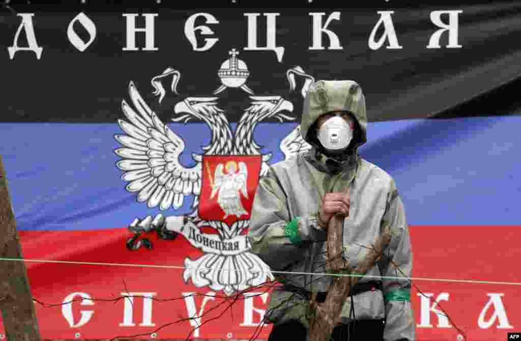 Проросійський бойовик охороняє барикаду з прапором так званої «Донецької республіки» біля захопленого відділку міліції у Слов'янську, 14 квітня 2014 року