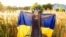 UKRAINE – Girl carries fluttering blue and yellow flag of Ukraine in field
