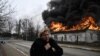 Жінка біля будинку, що горить після обстрілу в час масштабного вторгнення Росії до України. Місто Ірпінь Київської області, 4 березня 2022 року