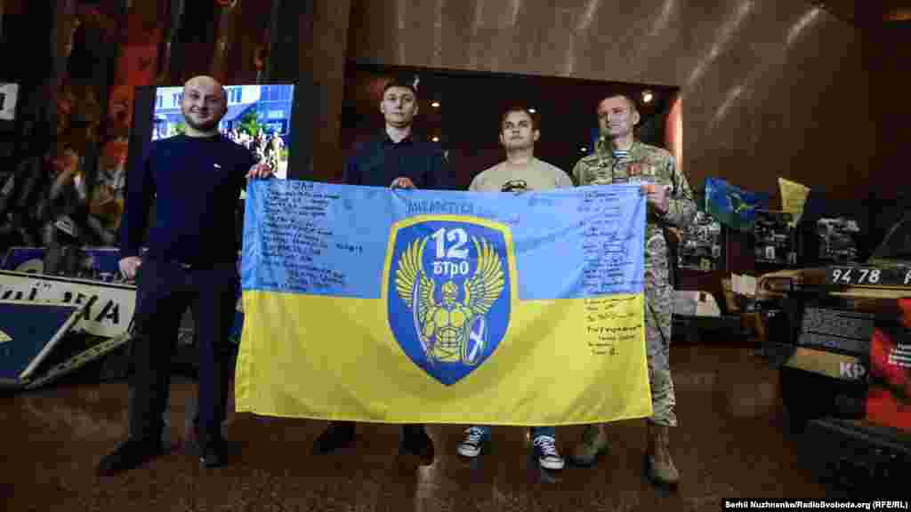 Бойцы 12-го батальона территориальной обороны «Киев» со своим флагом. Слева направо: Александр Полудень, метеоролог и командир отделения, сержант Вячеслав Цветинский, боец подразделения Илья Костин, Вячеслав Назаренко, командир 3-го взвода 1-й роты охраны 12-го БТрО «Киев»
