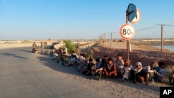 Afghan government soldiers sit by a bridge on the Tajik side of the border with Afghanistan on June 22.
