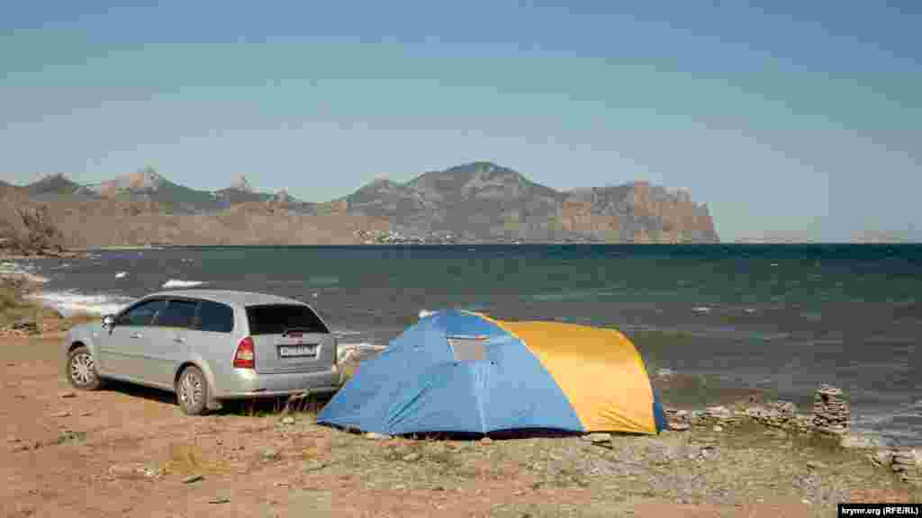 В многочисленных бухтах туристы ставят свои палатки. На побережье приезжают из разных уголков постсоветского пространства. Впрочем, эта палатка в цветах национального флага принадлежит владельцам машины с номерами группировки «ДНР»