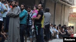 Люди стоят в очереди за хлебом в одном из пригородов Алеппо