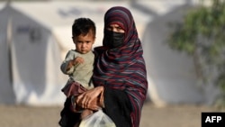 An Afghan woman holds a child as she arrives from Pakistan at a makeshift camp near the Afghanistan-Pakistan Torkham border in Nangarhar Province on April 20.