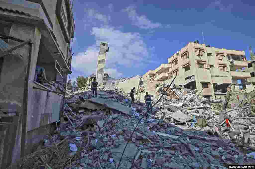 Палестинці шукають предмети, що можна утилізувати, серед уламків шестиповерхового будинку у Газі, зруйнованого внаслідок ранкового ізраїльського авіанальоту, 18 травня 