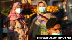 People wearing face masks walk through a market in Karachi. (file photo)