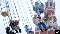 Дети катаются на аттракционе на фоне кремлевской башни. Москва, РФ, архивное фото