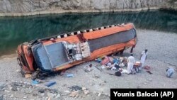 Locals stand by the damaged bus at the site of the accident in Khuzdar, a remote district in the Pakistan's southwestern Baluchistan Province on June 11.